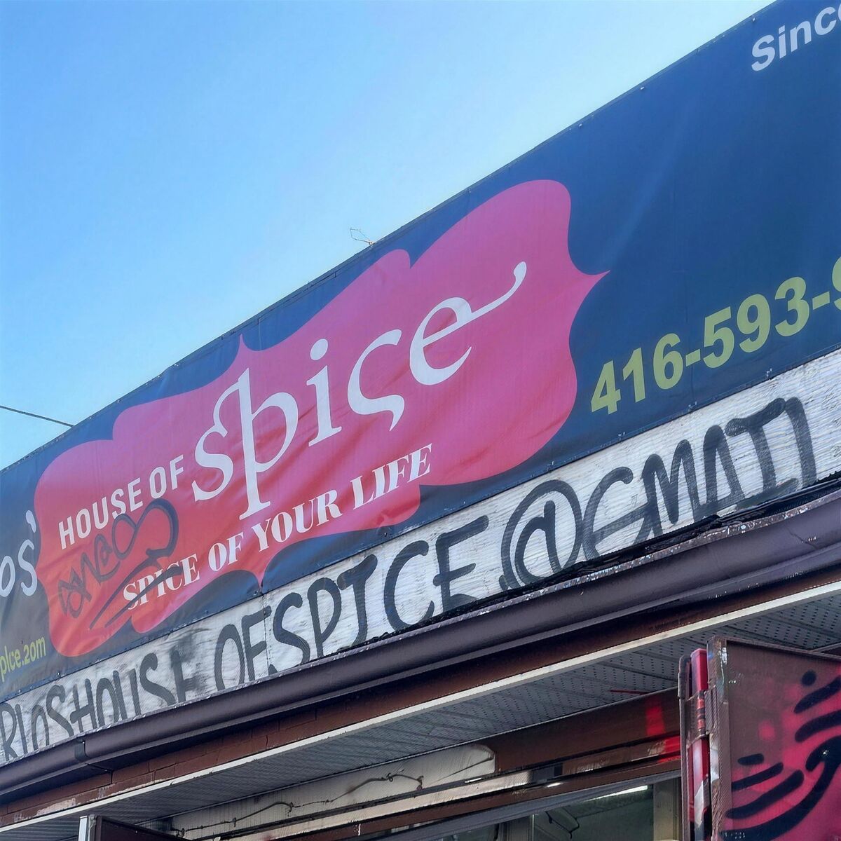 Close-up of the shop's printed banner sign, with a spray-paint tag across it